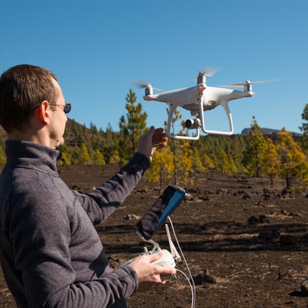 man flying a drone in an empty field